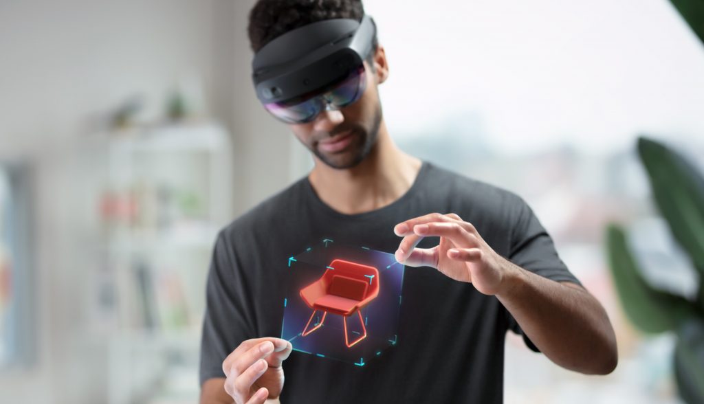 Homme portant un casque de Réalité Mixte, manipulant une maquette de chaise virtuelle avec ses mains